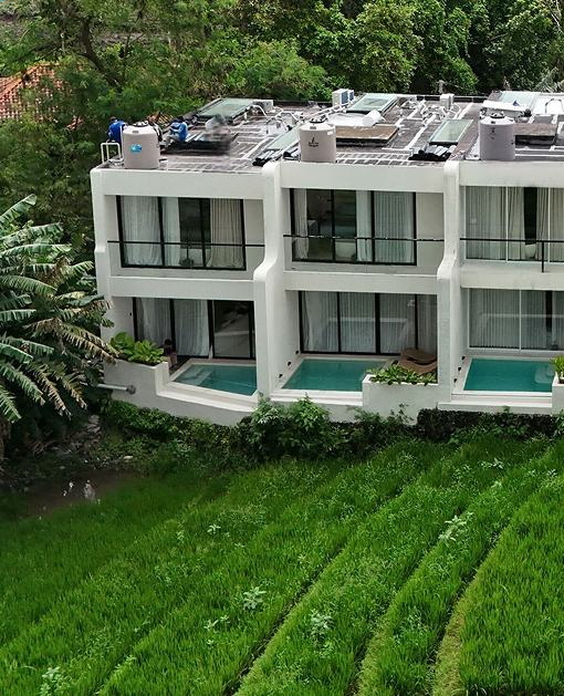 White villas with balconies and pools beside green fields